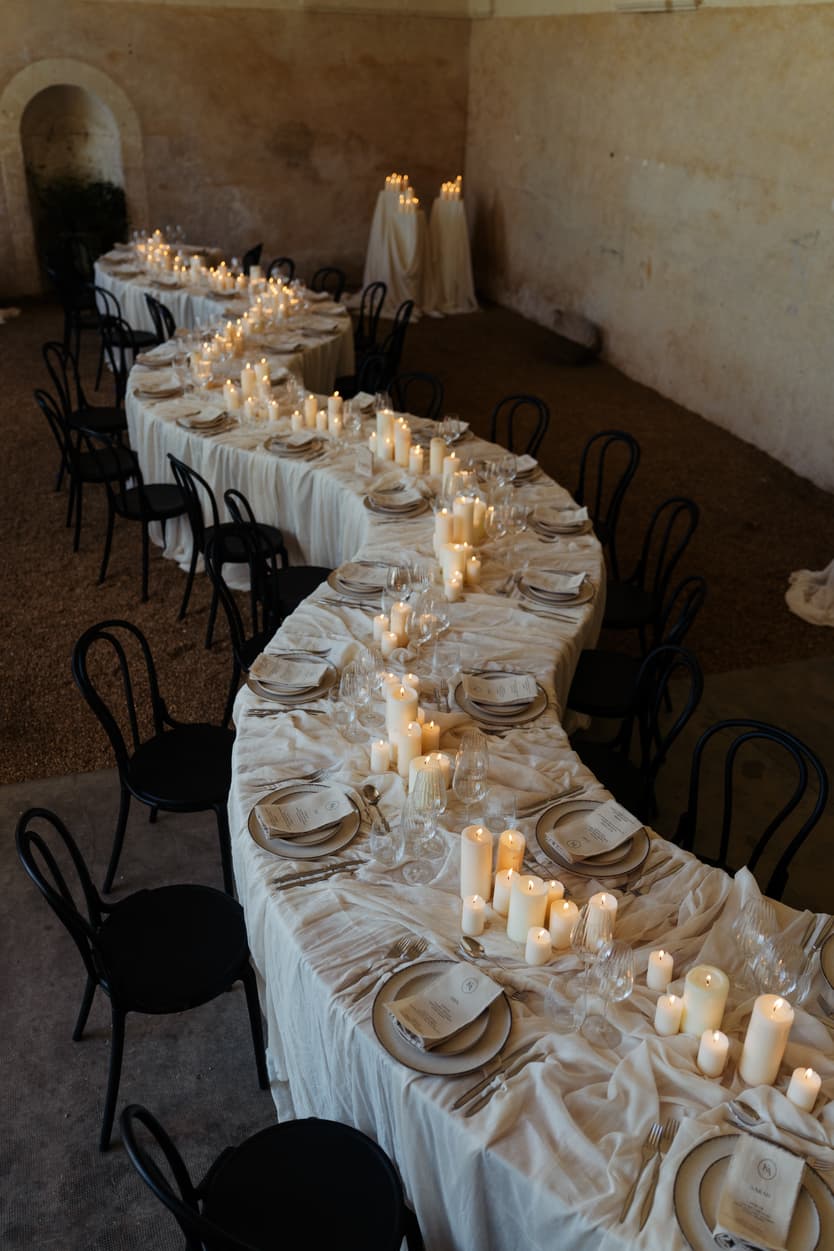 Draped silk welcome dinner table curving through the orangerie at Château du Grand Lucé, candles down its length