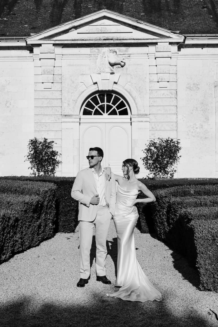 The couple in the orangerie doorway at Château du Grand Lucé in black and white, clipped topiary either side