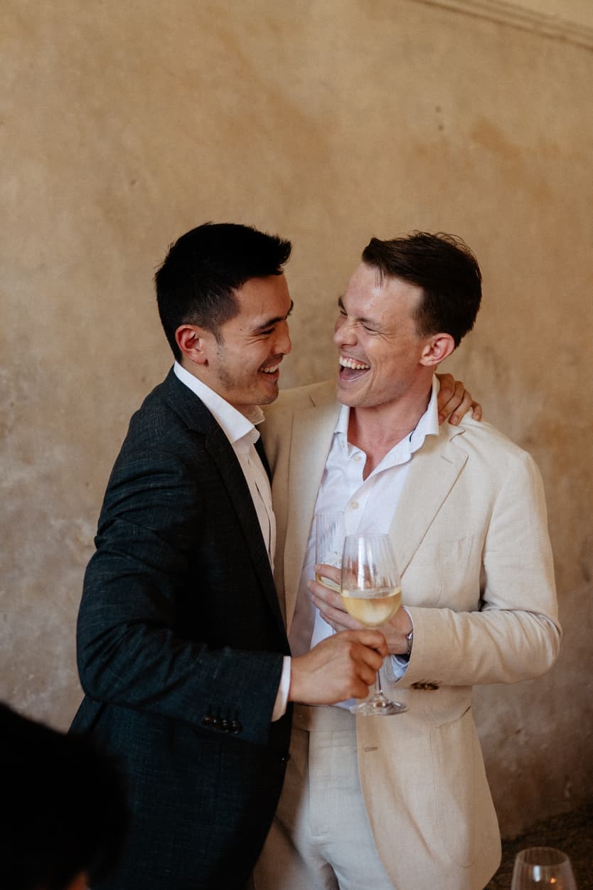 Two guests laughing over a glass of wine at the welcome dinner in the orangerie at Château du Grand Lucé
