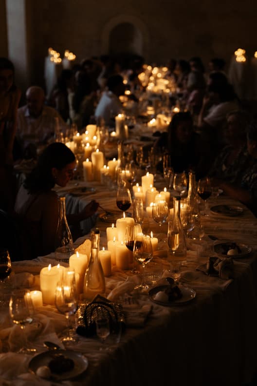 The welcome dinner at full candlelight, guests down both sides of the serpentine table in the orangerie