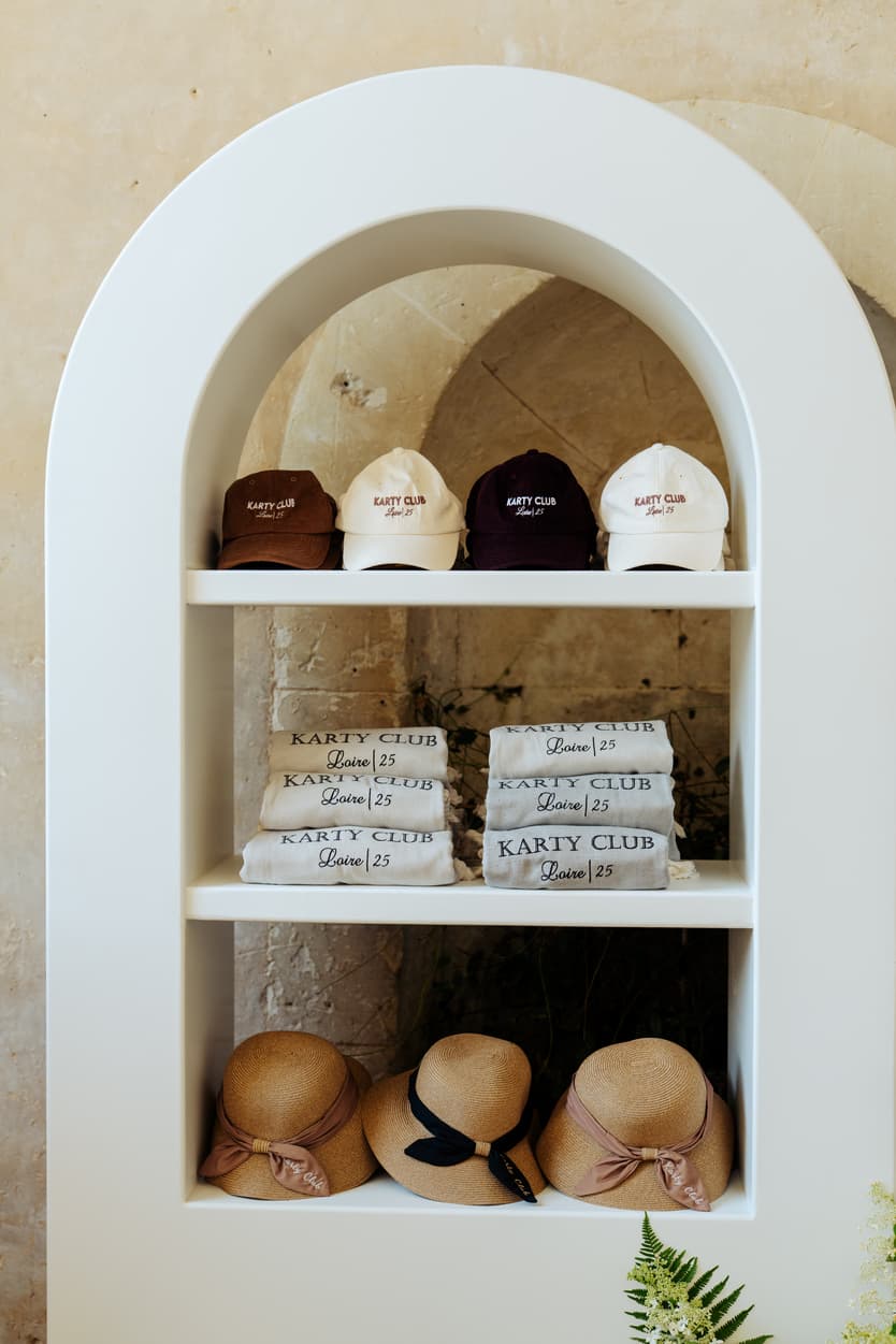Caps in burgundy and cream, folded towels and straw sun hats in the arched cabana at Château du Grand Lucé