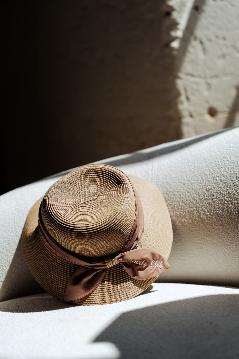 A straw sun hat with its Karty Club ribbon left on a lounger by the pool at Château du Grand Lucé