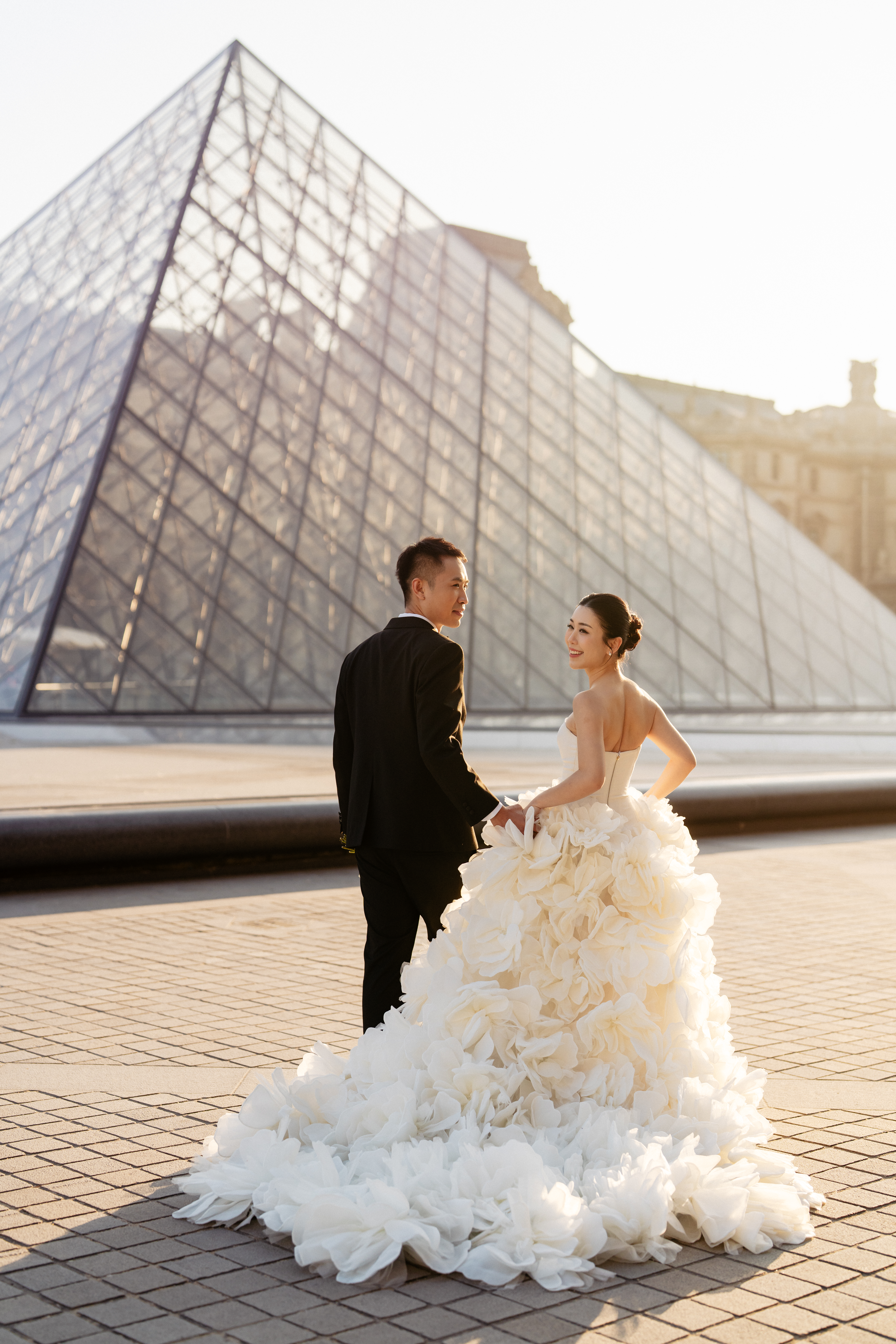couple in front pyramids at the louvre paris for their prewedding photos