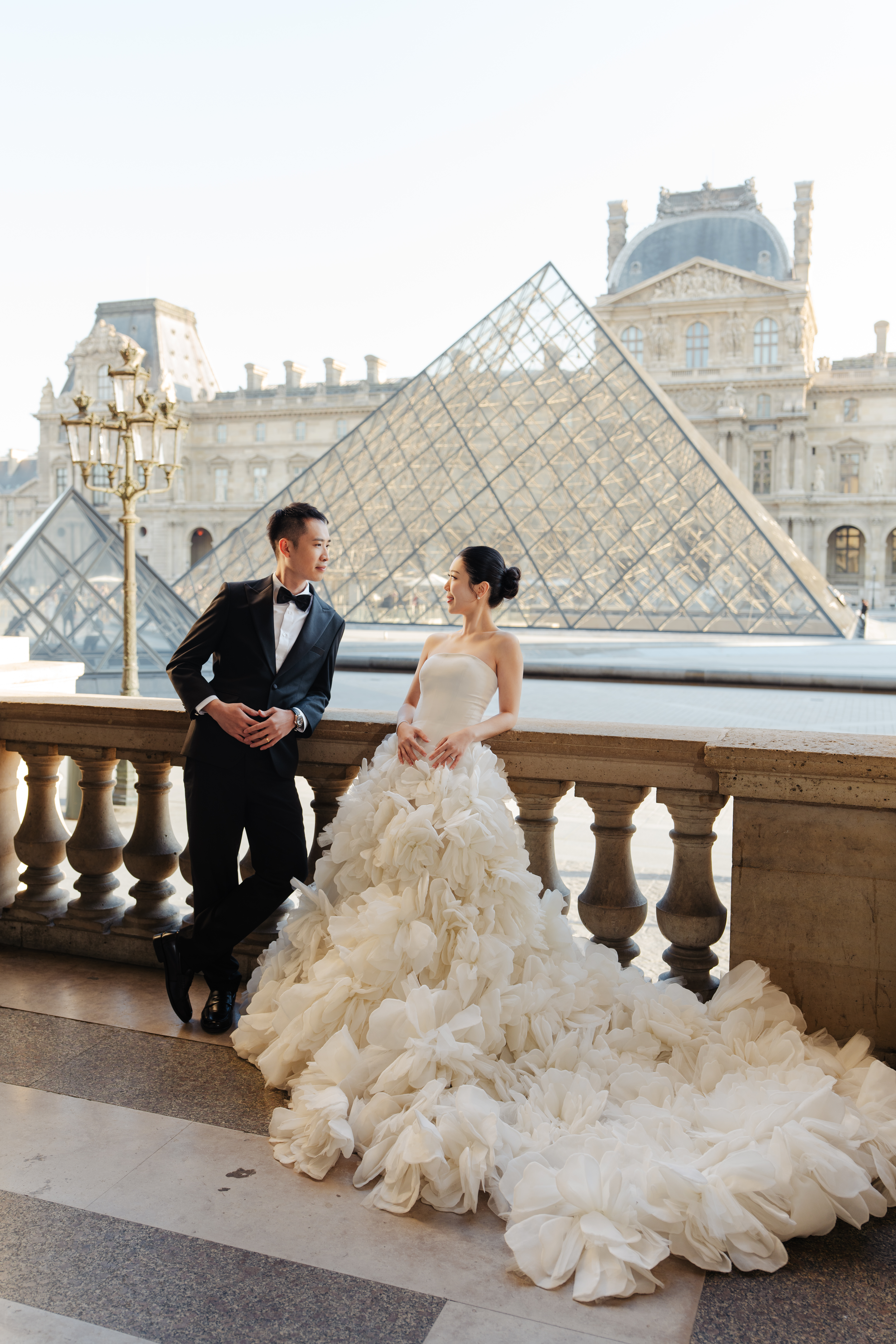 couple in front pyramids at the louvre paris for their prewedding photos